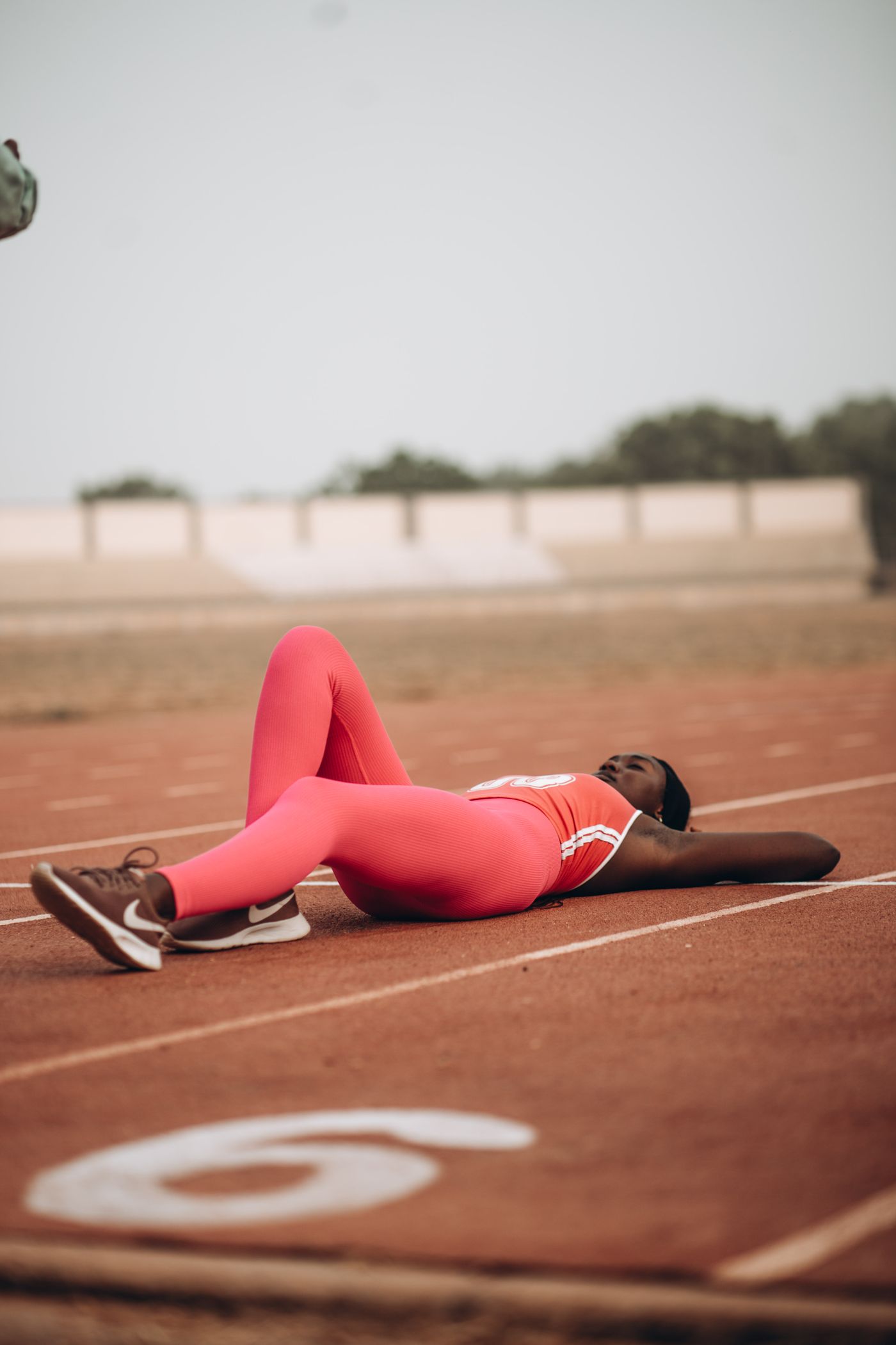 A runner lying flat on a track, resting after a race