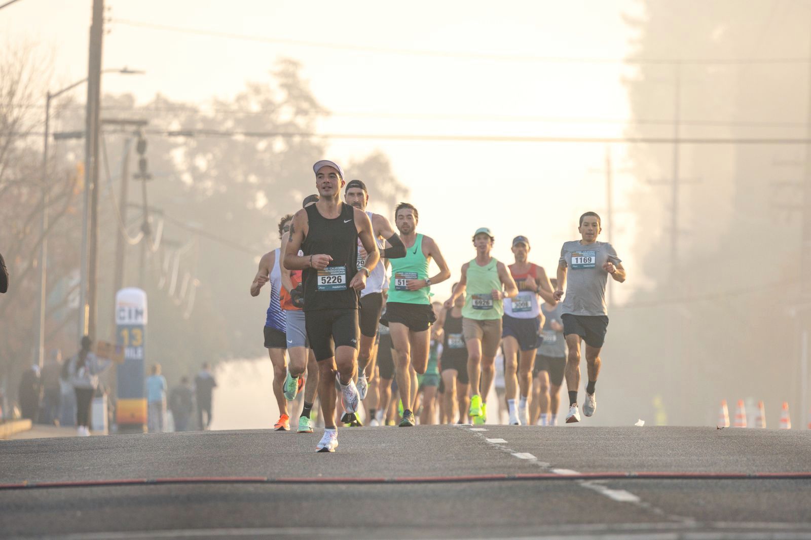 Marathon runners approaching through golden morning haze