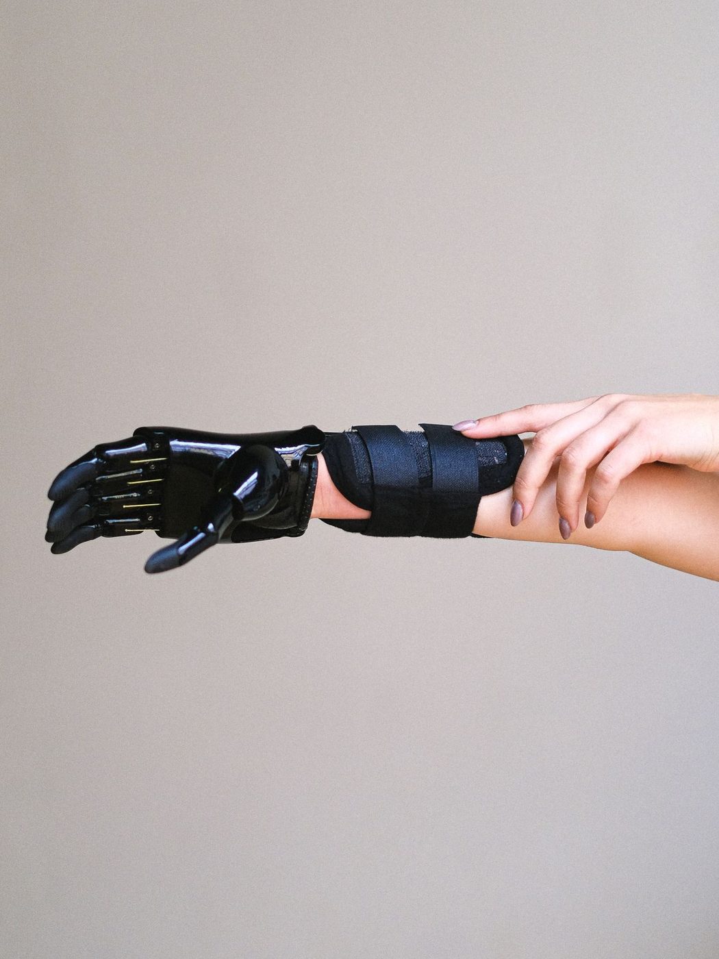 A glossy black bionic prosthetic hand worn on a forearm, held out in profile