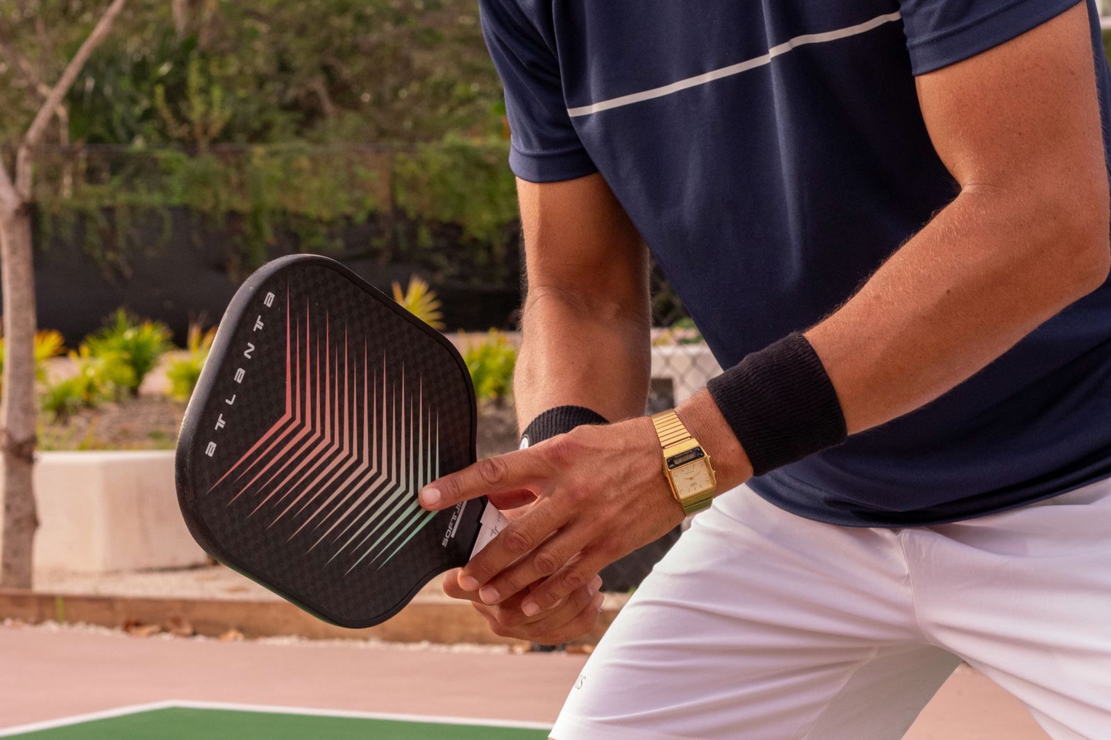 Pickleball player in a ready stance on an outdoor court, holding the paddle in front with both hands