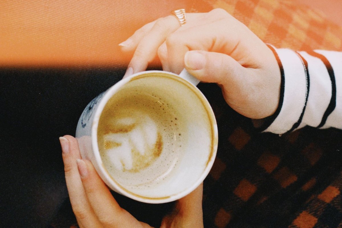 Two hands holding a cup of coffee with latte art